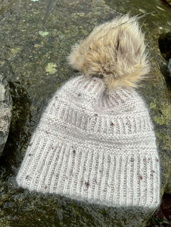 Lys Coffee Beanie med luvet dusk på en sten · strikkes rundt nedefra og op