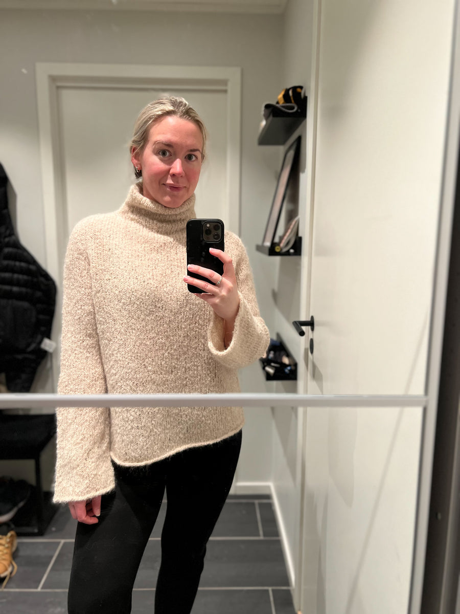 Spejlbillede af beige Latte Luxe Sweater med vide ærmer og buet nederkant · ærmerne har et diskret sving