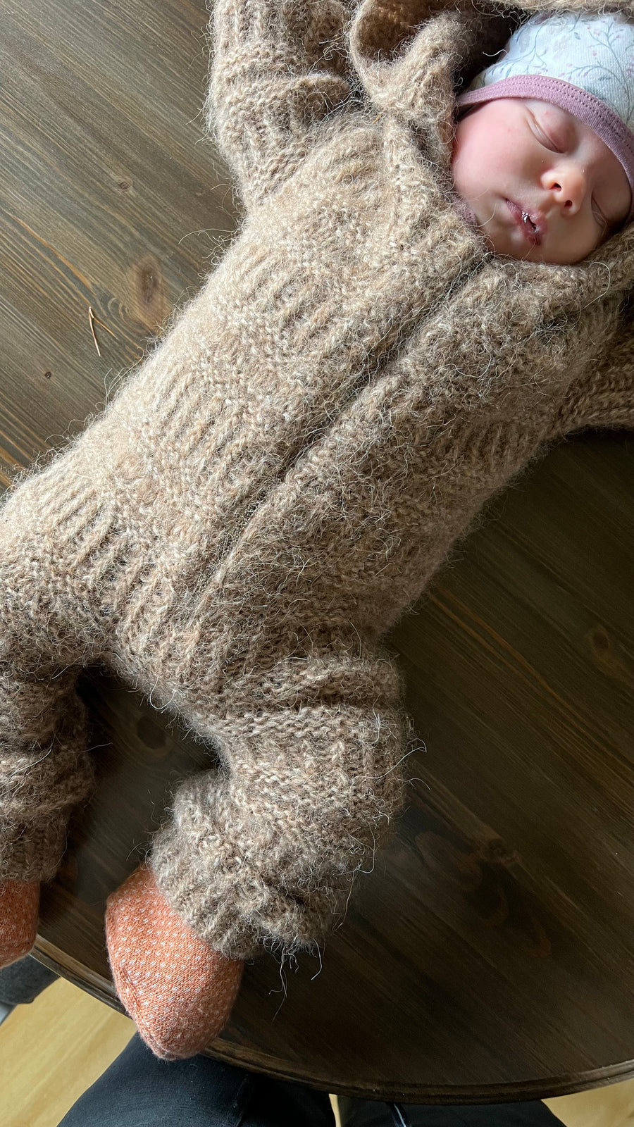 Sovende baby i Coffee Onesie med hætte, set oppefra · strukturen giver naturligt efter med babyen