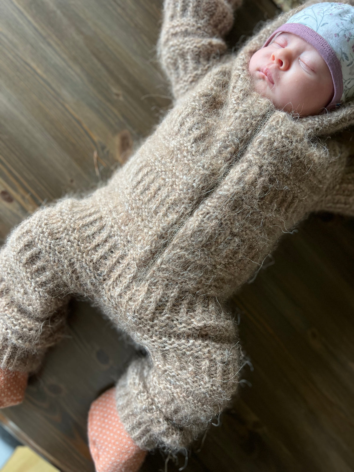 Baby i Coffee Onesie på et træbord, set fra siden · rib i dobbelt længde kan slås om