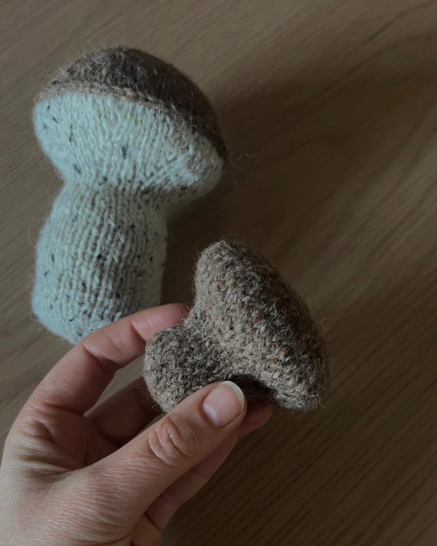 To strikkede sopper på et lyst trebord, hatten i hånden · begynner med magic ring