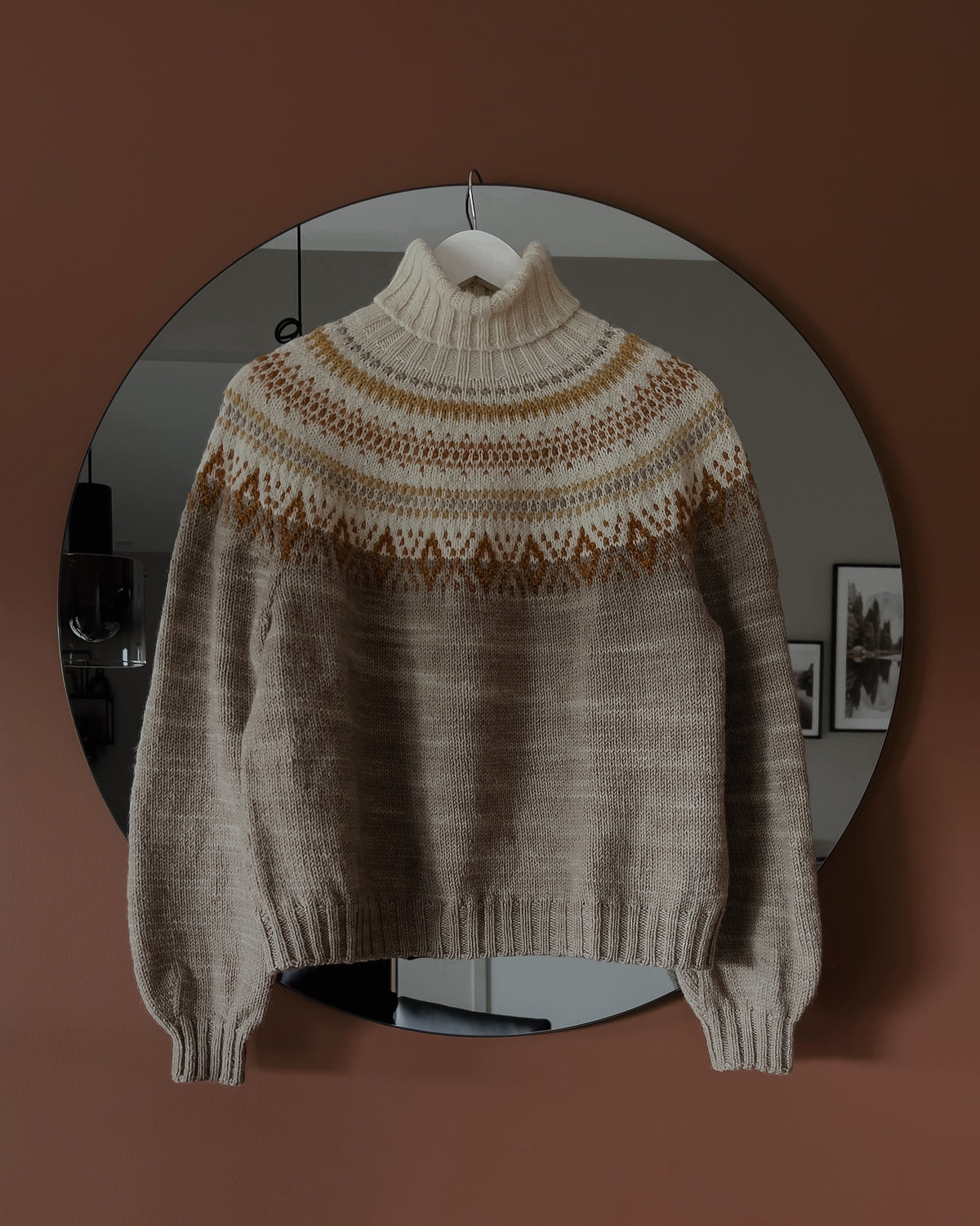 Tales of Patagonia Sweater på galge framför en rund spegel · inga axelsömmar
