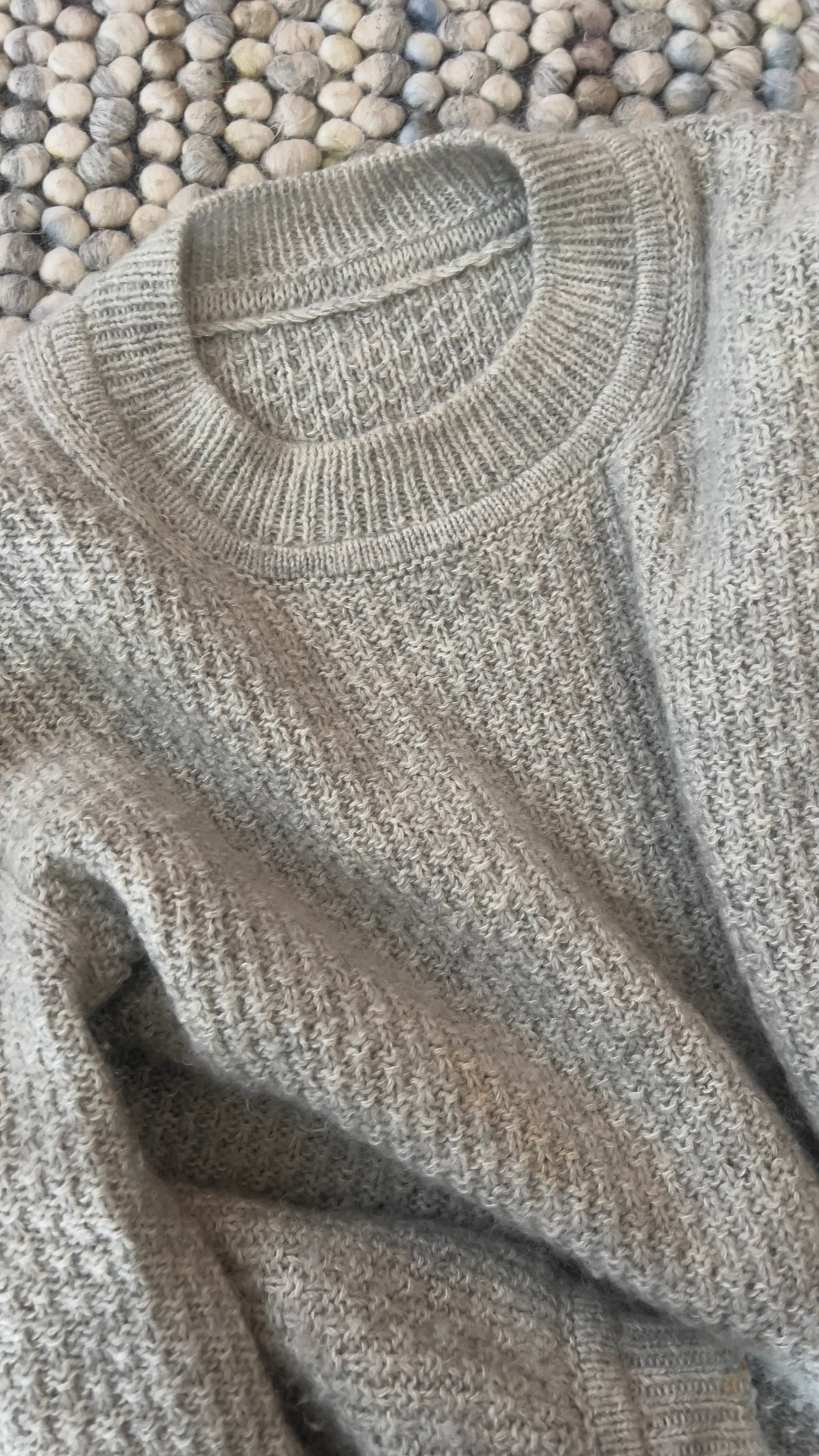 Ribbet halskant og struktur på Mistlight Sweater, liggende på tæppet · skulderdelene slås op hver for sig