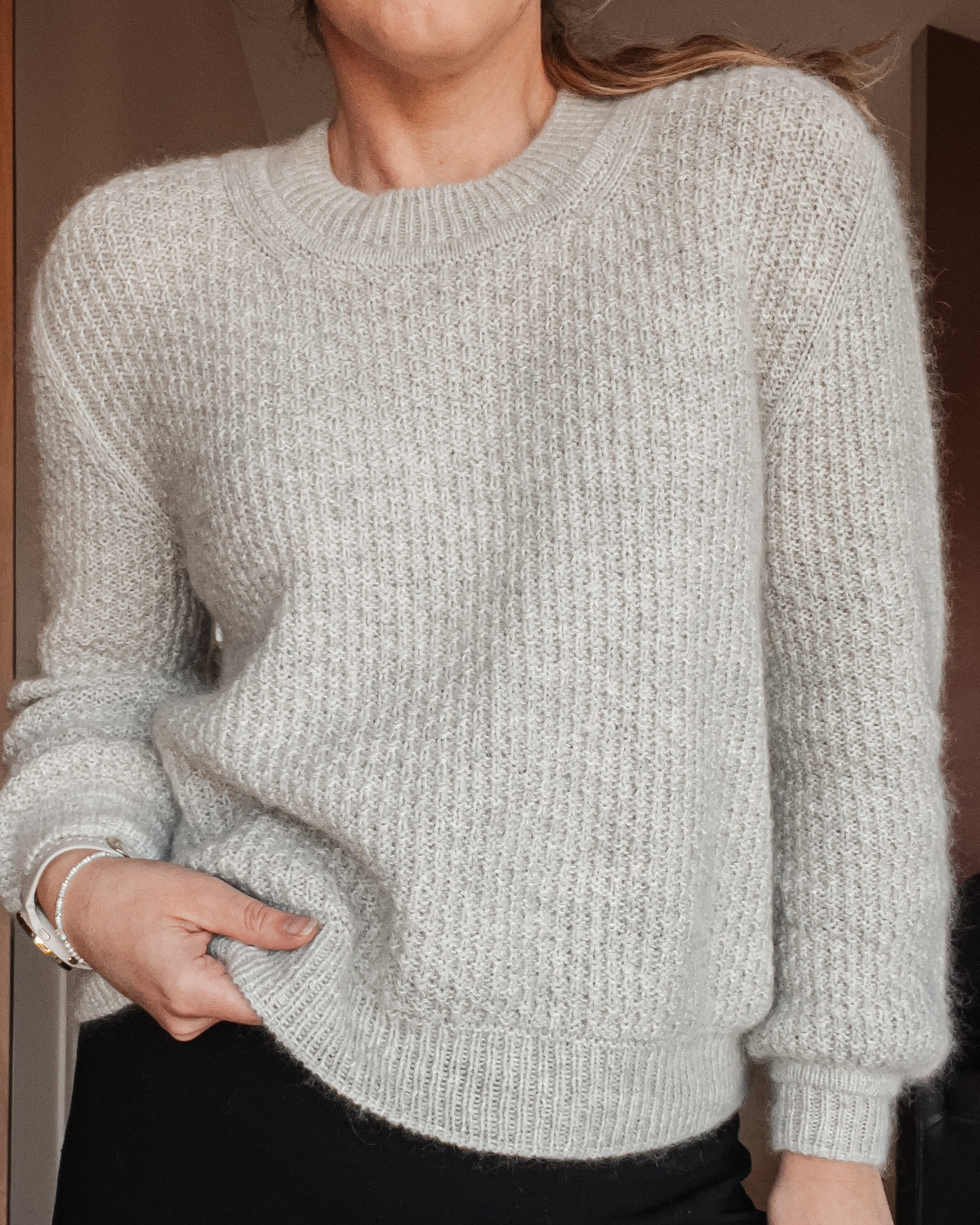 Nærbillede af Mistlight Sweater båret, med rund hals og ribbet nederkant · ærmer og krop strikkes rundt i strukturen