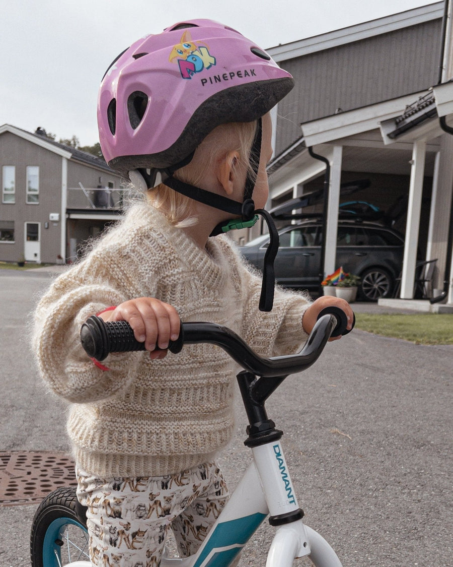 Barn med hjelm på løbecykel, set fra siden · gentaget mønster, der er rart at strikke