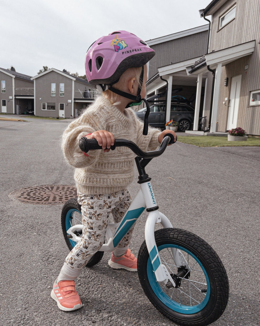 Barn på løbecykel i Coffee Sweater Mini, set fra siden · håndfarvet mohair giver sit eget udtryk
