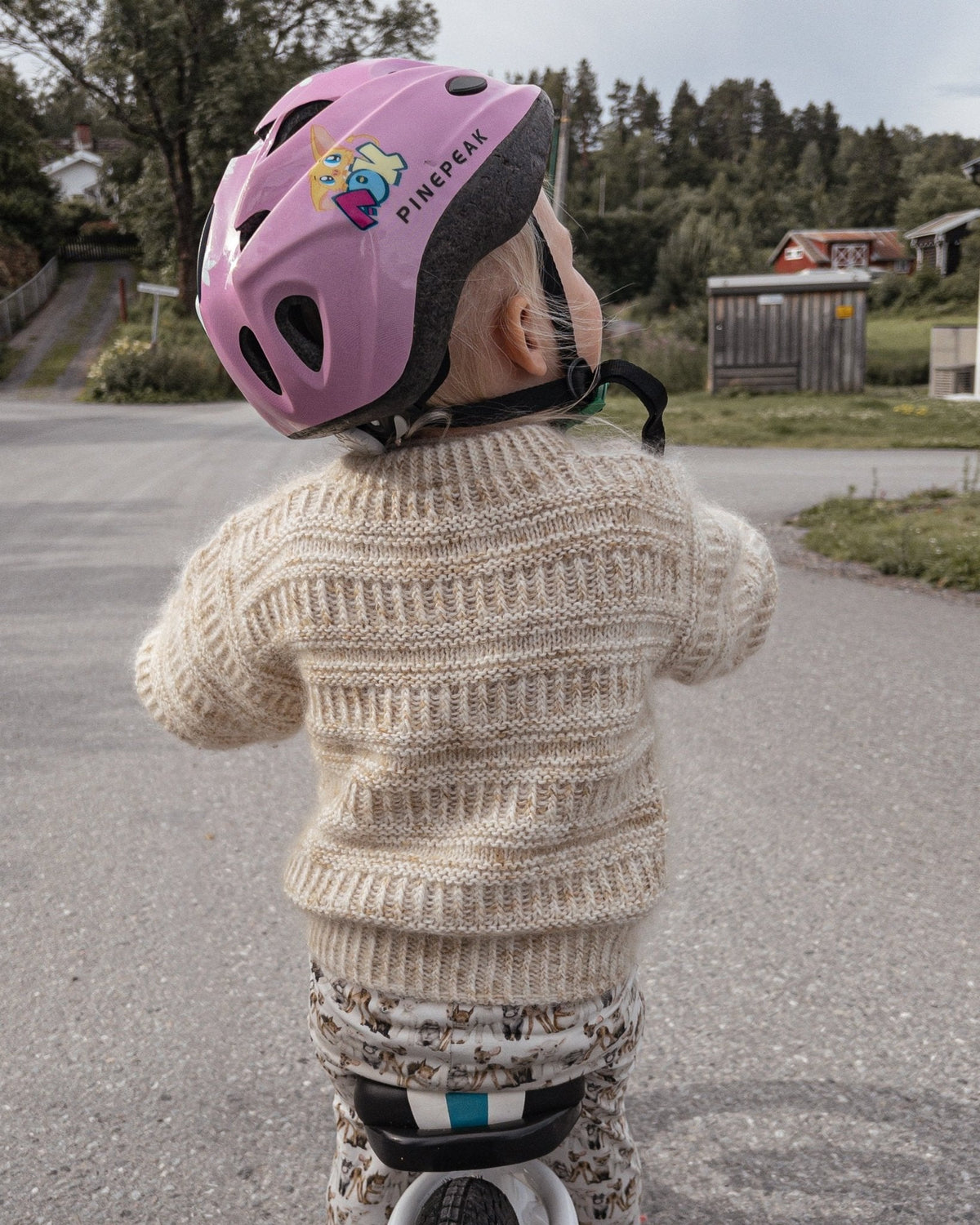 Barn på løbecykel i Coffee Sweater Mini, set bagfra · lidt oversize