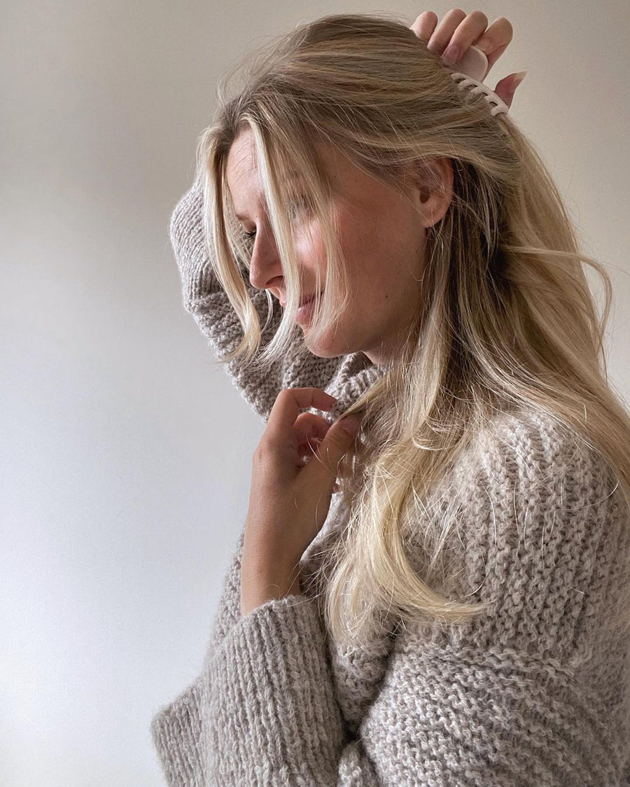 Dawn Sweater fra siden med løftet arm, struktur på overdelen og ribbet ærme · ærmerne strikkes ned til ribkanten